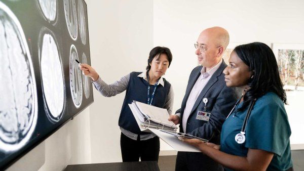 Adam Boxer (center) looks at MRI scans with Professor Nicki Yang and Whintey Walker, R N.