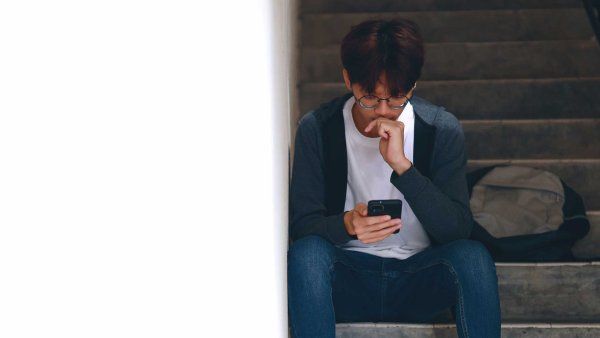 A teenager somberly looks at his phone.