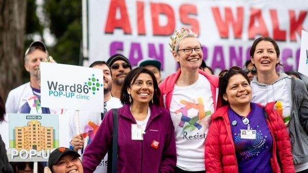 Staff and community members standing in front of an AIDS Walk San Francisco banner