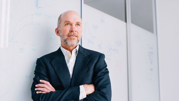 Grae Davis leans against a white board with his arms crossed.
