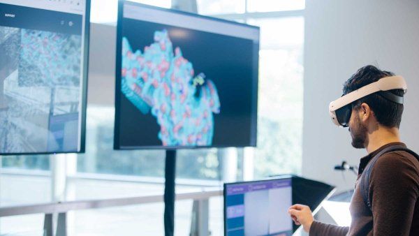 An attendee to the Byers Lecture event wears a virtual headset as he explores a cellular model on a computer screen.
