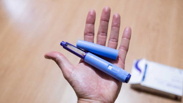 A hand holding a semaglutide injection pen as a medical treatment for the prevention and control of obesity and diabetes.