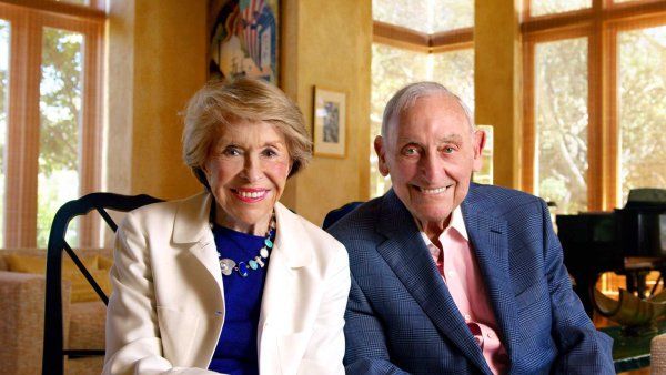 Joan and Sandy weill sit together in a warm indoor setting.