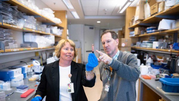 Janel Long-Boyle and Christopher Dvorak look at a blood sample in a lab.