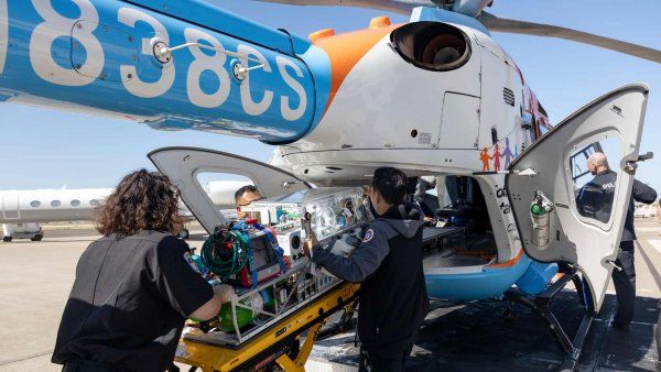 A group of emergency medical professionals load an incubator onto a U C S F Benioff Children's Hospitals helicopter for emergency transportation.