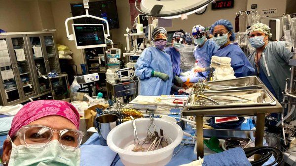 A group of all women surgeons and medical professionals take a selfie during a surgery.