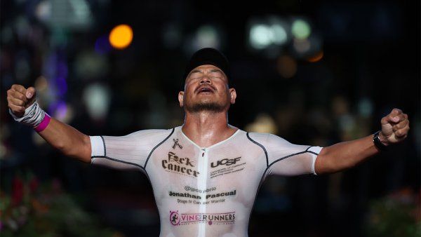 Jonathan Pascual crosses the finish line at the 2024 VinFast IRONMAN World Championship with his arms in the air and his head looking up in relief and triumph.