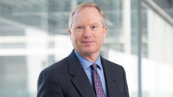 Brian Smith in a suit and tie smiles.