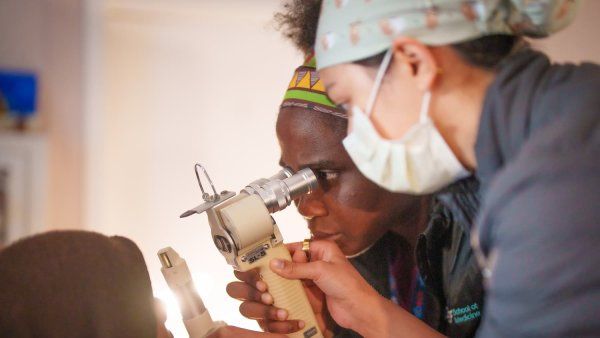 Two medical practictioners conduct an eye exam on a patient.