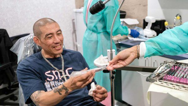 A patient at Citywide Dental smiles as receives a toothbrush from a dentist.