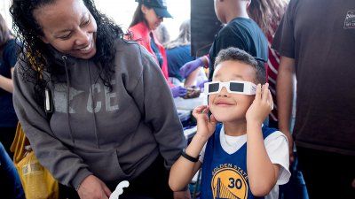 Karen Bell watches her son Isiah Hill, 6, experiment with 3D glasses at the Neurobiology booth at the Bay Area Science Festival Discovery Day