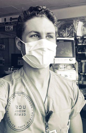 Portrait of Max Rausch in scrubs and a face mask at the hospital.