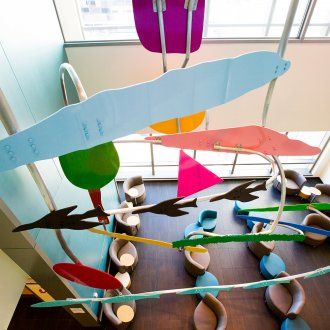 A colorful mobile made of geometric shapes hangs above the lobby of the Ron Conway Family Gateway Medical Building