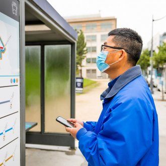 A man looks at the shuttle schedule posted on the bus stop