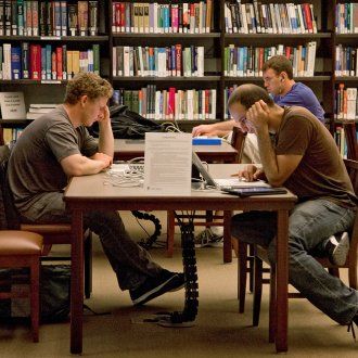 Several people read books set out on a table in the FAMRI Library