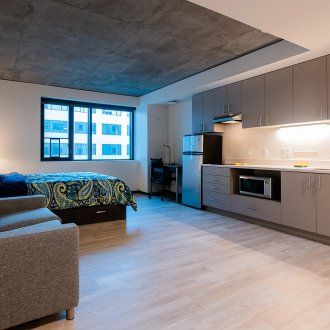 A spacious studio unit with a concrete ceiling, kitchen, and living area