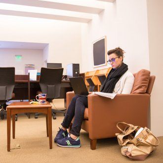 A student sits in an armchair with her laptop in the FAMRI Library