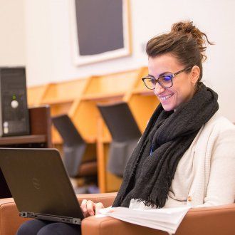 Postdoc Benedetta Milanini laughs as she looks at her laptop in the FAMRI Library
