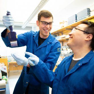 Reuben Saunders and Dian Yang laughing while Reuben holds up a pipette