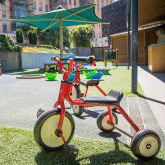 A tricycle sits outside in the play area