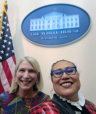 Diane Havlir and Susana Rojas of Latino Task Force in front of a sign for the White House