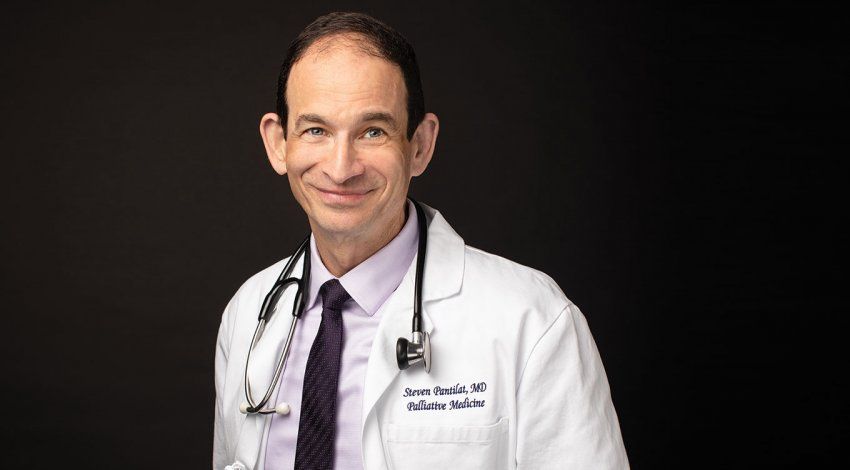 Photo of Steven Pantilat, MD, in a white doctor’s coat with a stethoscope draped around his neck, in front a black background.