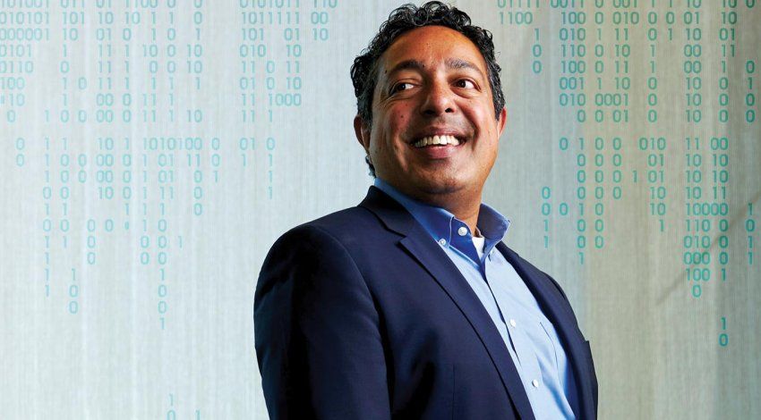 Portrait of Atul Butte with binary code illustration in background.