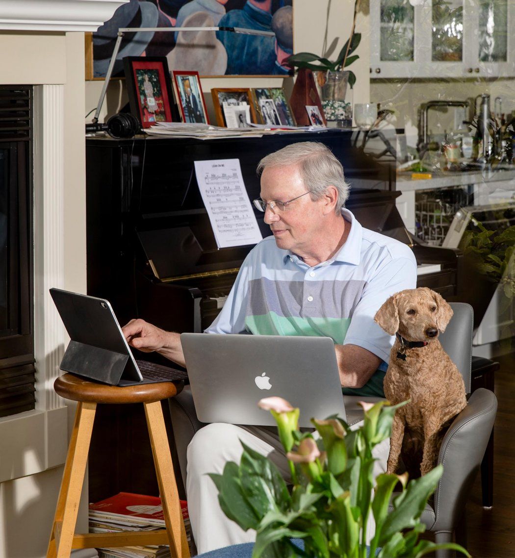 Photo of Robert Wachter, MD, sitting at his computer in his home, with his dog by his side.