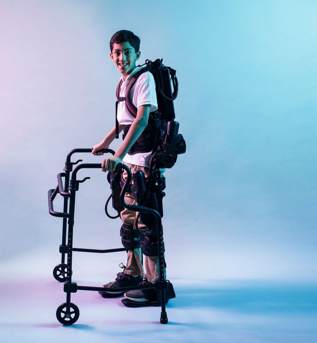 Photo of Dilan Horwitz, piloting a robotic exoskeleton in front a blue and purple background..