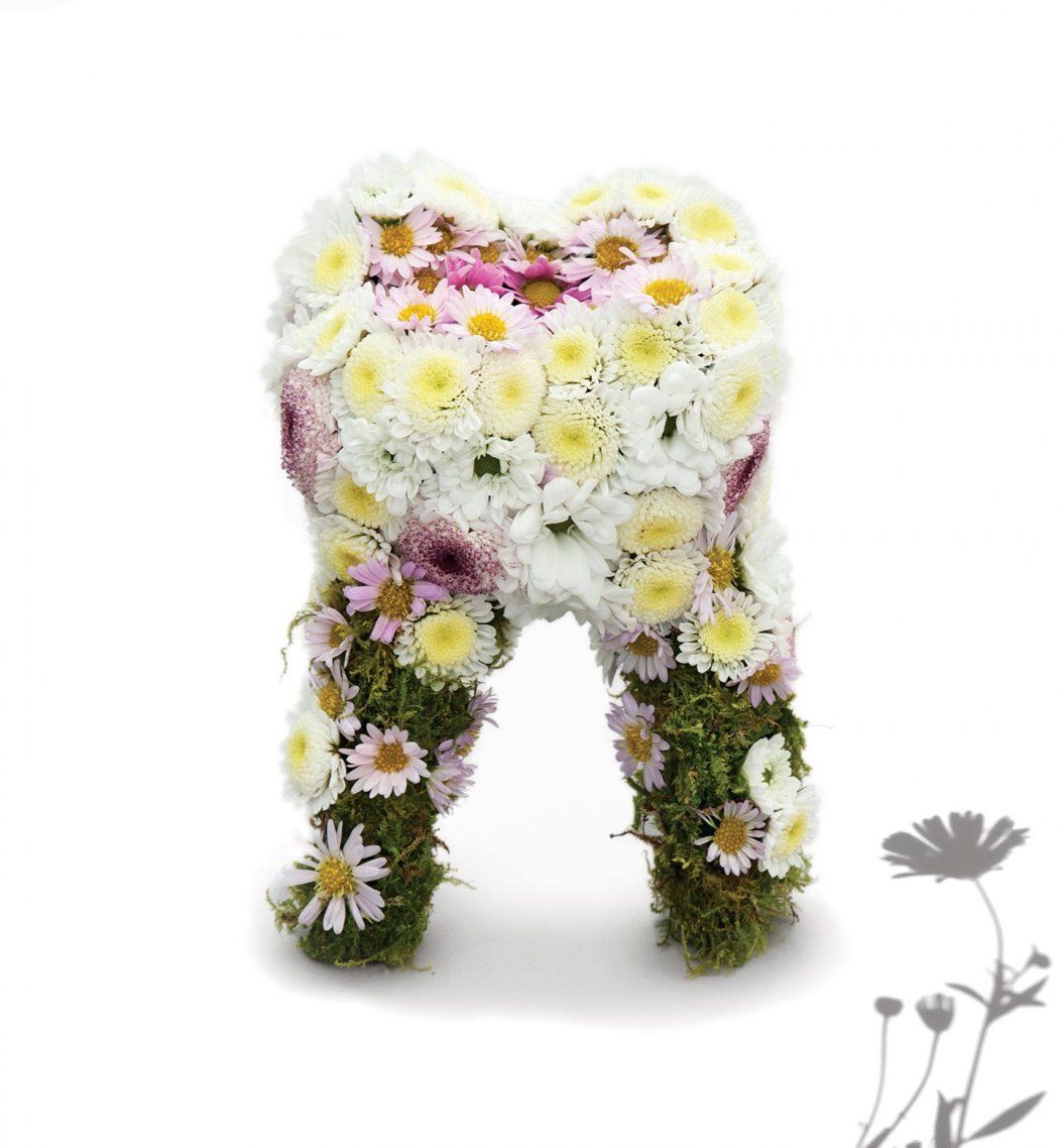 A sculpture of a human tooth made out of flowers and moss.