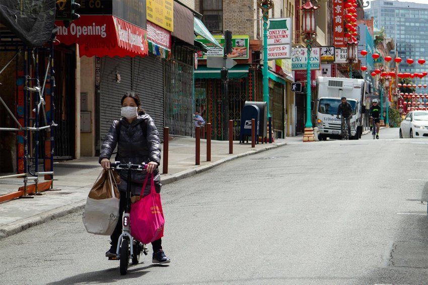 A resident wearing a face mask in Chinatown, San Francisco, is transporting groceries on a bike during the shelter-at-home Covid-19 crisis.