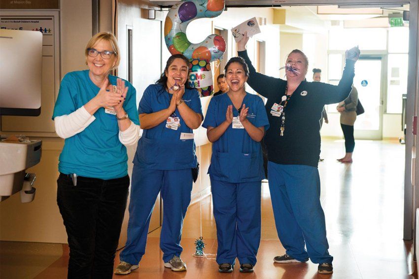 Four nurses cheer with a balloon and noise makers.