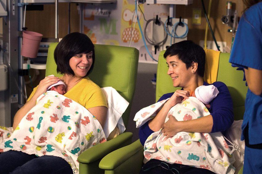 Two mothers hold their newborn twins.