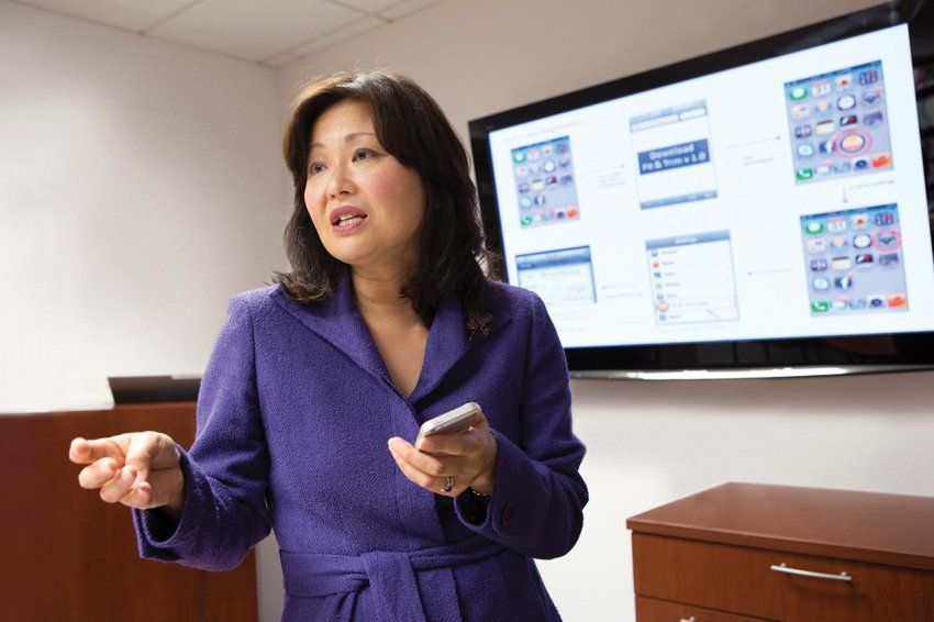 Yoshimi Fukuoka speaks in front of a digital screen.