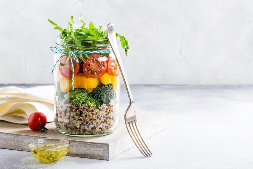 Homemade salad in glass jar with quinoa and vegetables.